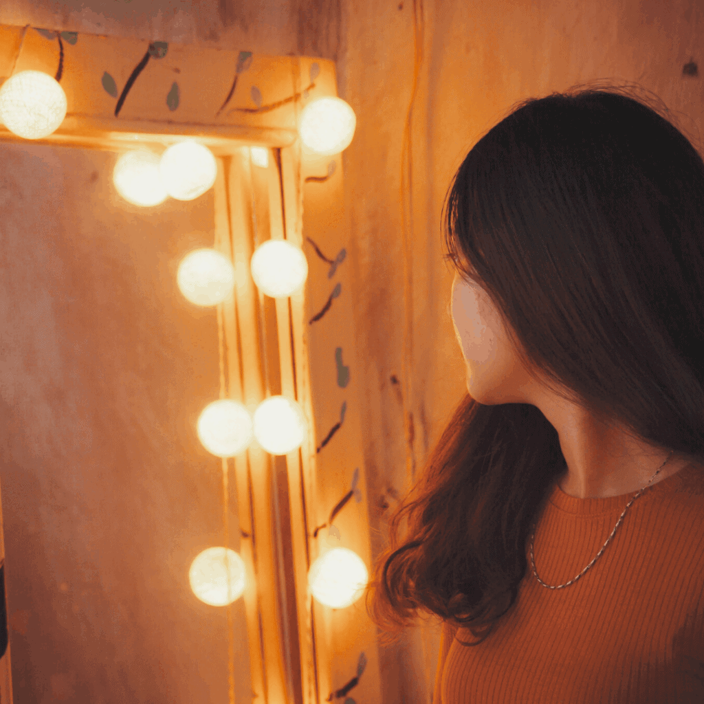 woman facing mirror with lights