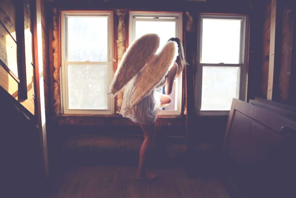 woman in white dress with wings about to jump on a window
