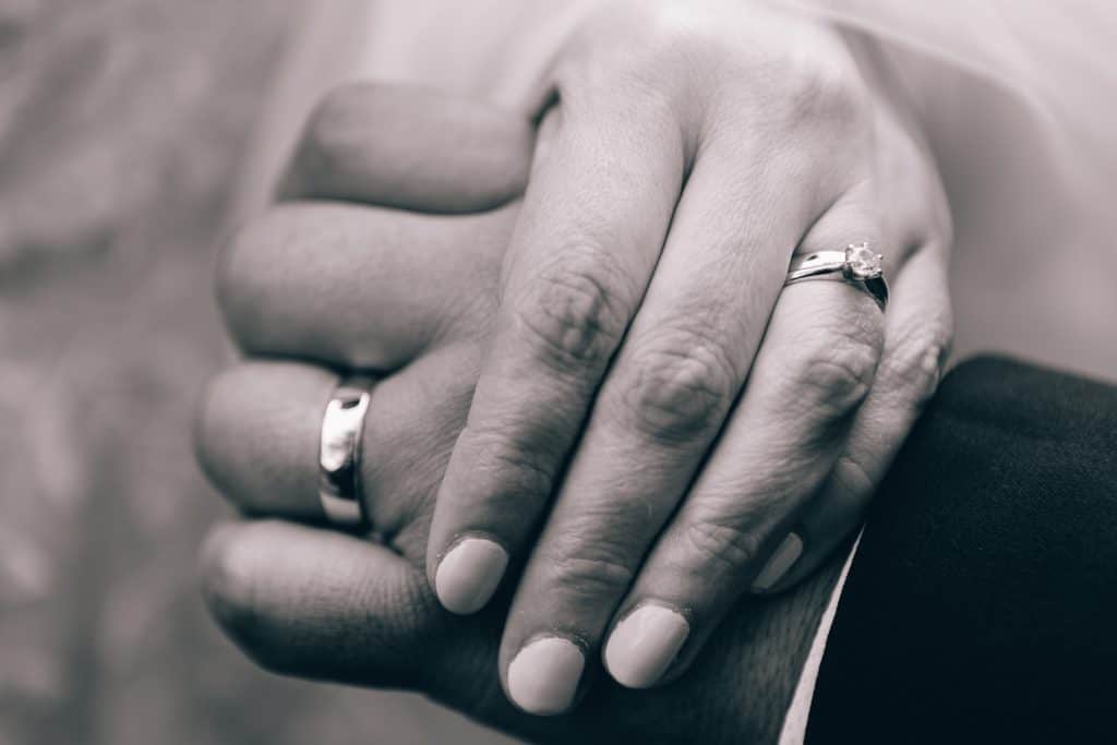 black and white close up photo of couple holding hands wearing their wedding rings
