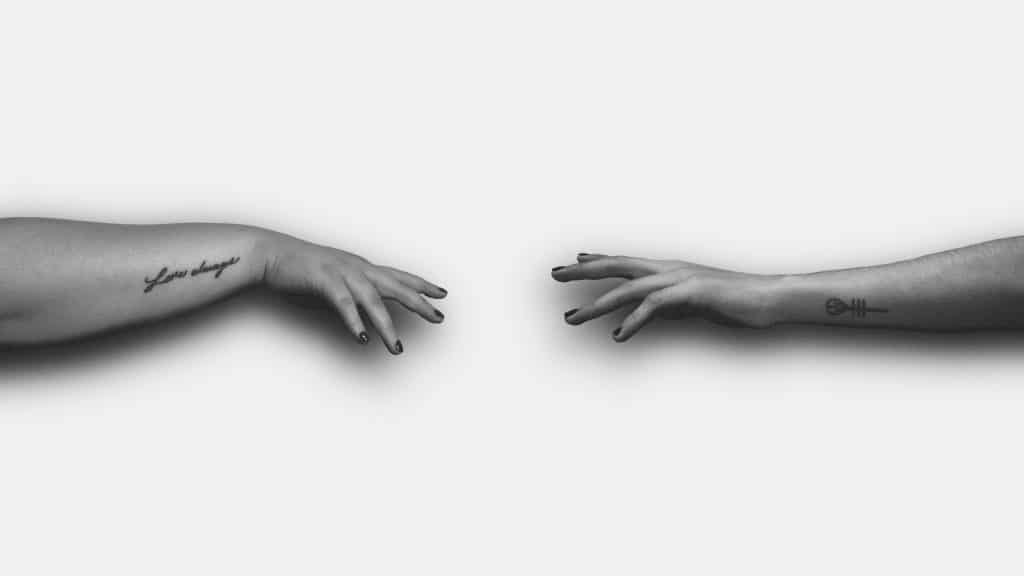 black and white photo of 2 hands apart trying to reach each other