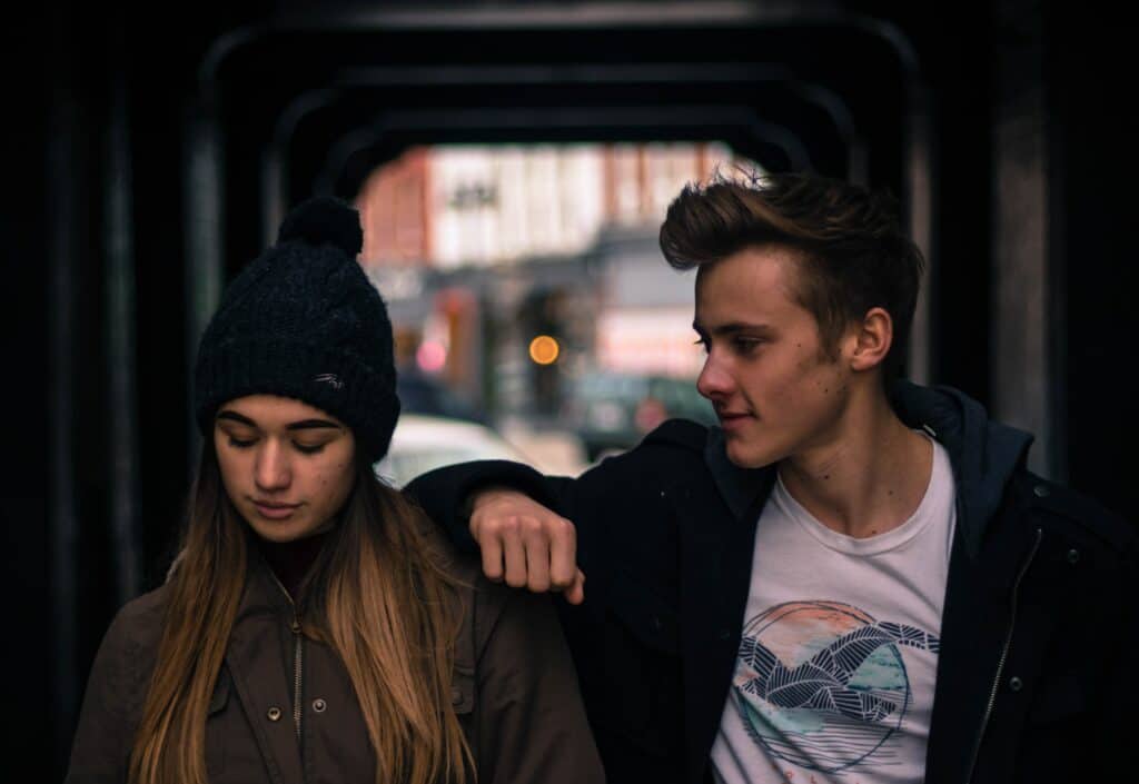 photo of young lovers walking together in the street