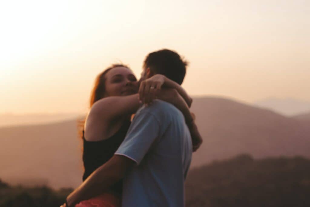 a couple hugging each other and a mountain view behind them