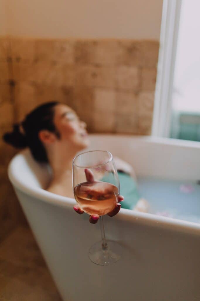 a photo of a woman inside a bath tub enjoying her time with a glass of wine